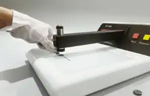 Opérateur en laboratoire manipulant l'ouverture de diaphragme sous le bras du densitomètre DT-300 PLUS pour l'analyse de films radiographiques